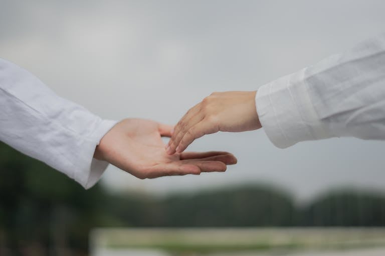 Two people holding hands in front of a white background